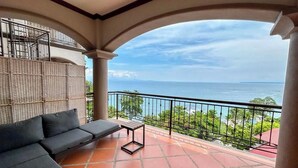 A balcony with a sofa and a small table, overlooking a scenic view of the ocean. - Spacious apartment for 8 people in Playa Blanca | exclusive beach access (Playa blanca, punta leona)