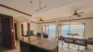 A spacious living area with a large window, a dining table, and a kitchen island. - Spacious apartment for 8 people in Playa Blanca | exclusive beach access (Playa blanca, punta leona)