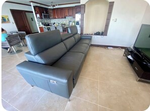 A living room with a sofa, a TV, and a kitchen in the background. - Spacious apartment for 8 people in Playa Blanca | exclusive beach access (Playa blanca, punta leona)