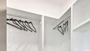 A walk-in closet with open shelves and a metal rod for hanging clothes.