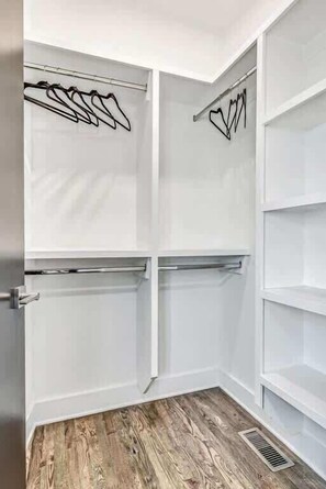 A walk-in closet with open shelves and a metal rod for hanging clothes.
