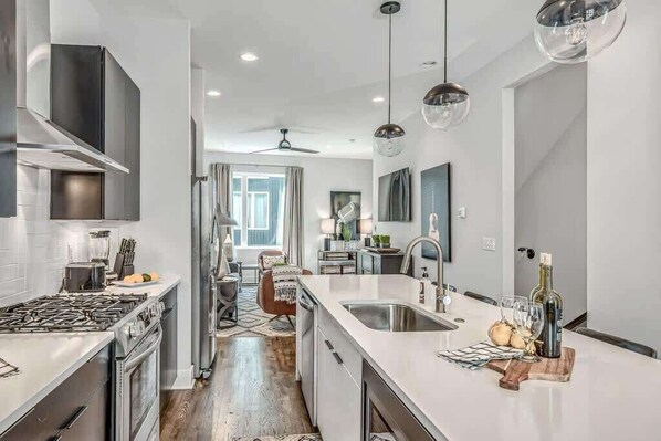 A modern kitchen with a central island, stainless steel appliances, and pendant lighting.