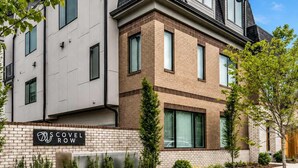 Un immeuble résidentiel moderne à plusieurs étages, avec une façade combinant brique et béton, de grandes fenêtres et une enseigne bien visible indiquant le nom « COVEL ROW ».