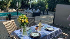 An outdoor dining area with a pool in the background. - Gite1 T3 with swimming pool in the heart of the vineyards (34310 - CAPESTANG)