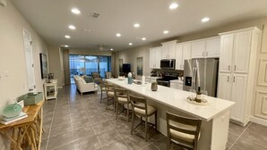 A spacious kitchen with a central island, white cabinetry, and stainless steel appliances. - Late Summer at Solara • Private Pool• Walk To Clubhouse (Kissimmee)