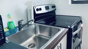 Una cocina con un lavaplatos de acero inoxidable, una estufa y una ventana.