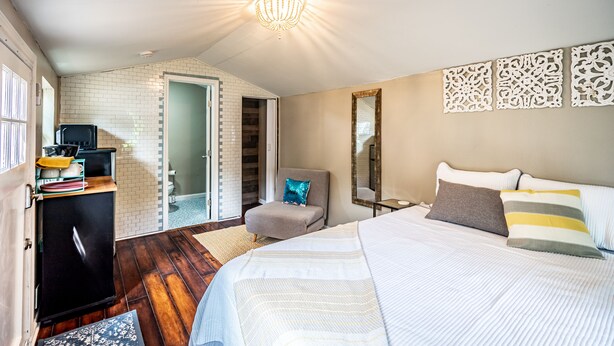 A bedroom with a bed, a chair, a desk, and a mirror. - Tiny house in Bishop Arts! (Dallas)