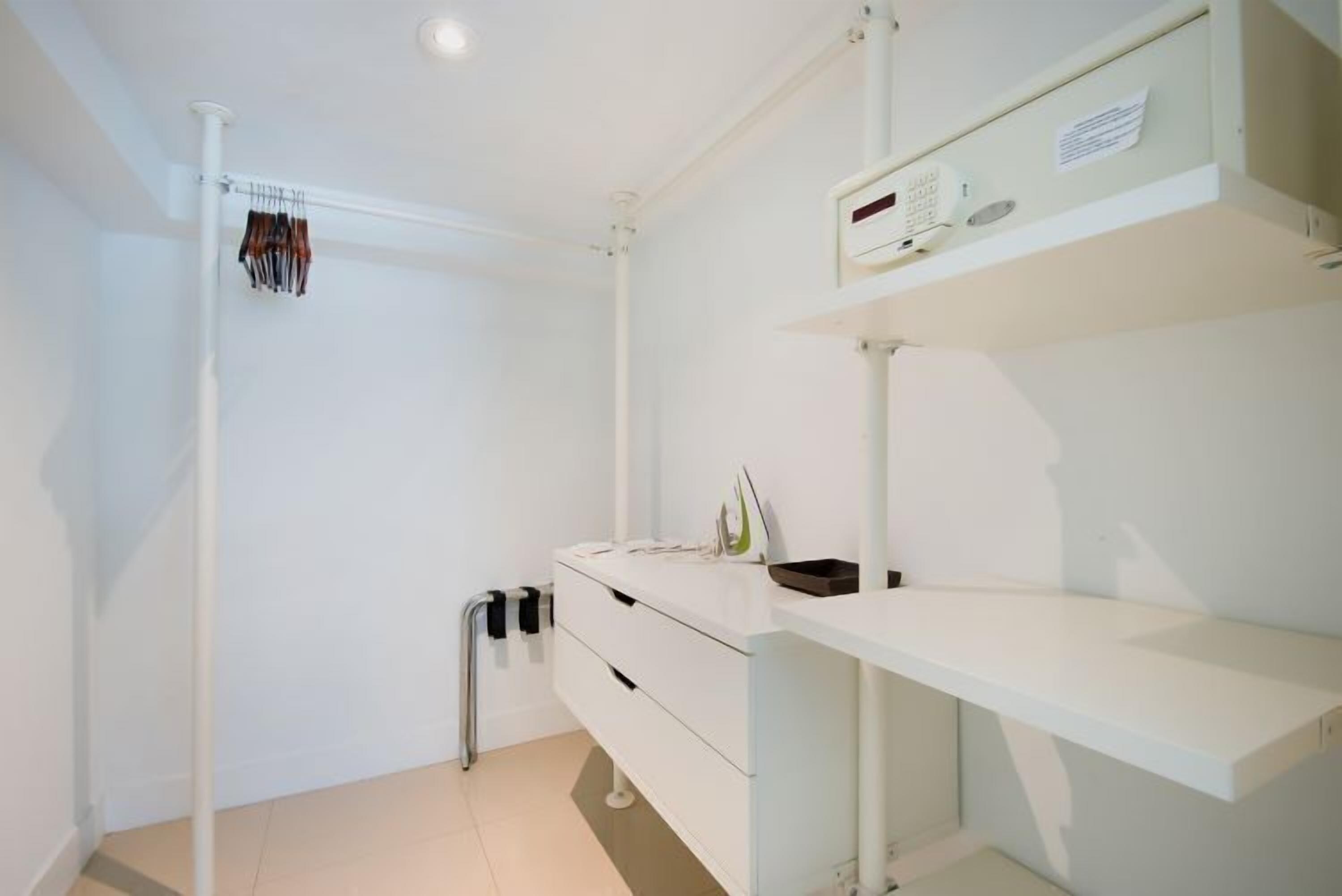 Un baño moderno con accesorios blancos, un perchero y un estante con artículos de aseo.