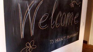 Ein Willkommensschild mit dem Schriftzug "Welcome to Mount Pleasant" vor schwarzem Hintergrund.