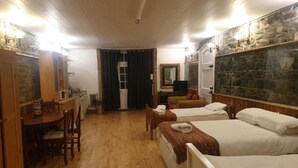 Ein Hotelzimmer mit zwei Einzelbetten, einem Holztisch mit Stuhl, einem kleinen Tisch und einem Spiegel.