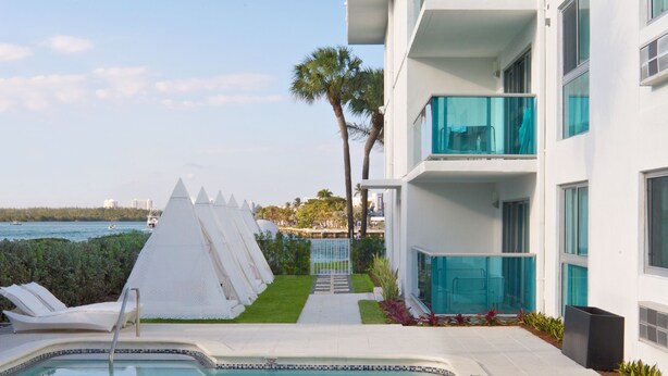 Hotel modern amb piscina, façana blanca i balcons amb baranes de vidre.