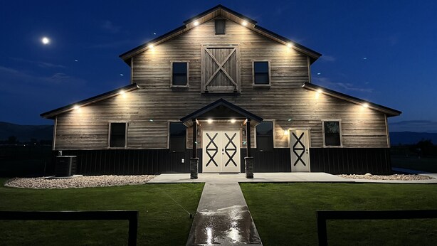 A two-story wooden house with a large barn door and a well-lit front entrance.