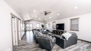 A spacious living room with a large sectional sofa, a flat-screen TV, and a ceiling fan.