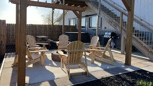 Un patio in legno con poltrone Adirondack, una vasca idromassaggio e un barbecue.