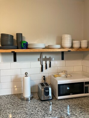 Kitchen area with granite countertop, toaster, microwave, and ample storage for kitchenware.