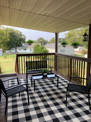Relax in this serene outdoor seating area with a checkered floor, comfortable chairs, and a charming potted plant.