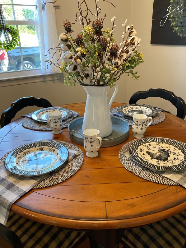 Enjoy meals with family and friends at this dining table, set for four with a beautiful floral arrangement and matching tableware.