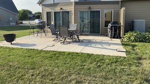 A house with a patio area featuring outdoor furniture, a barbecue grill, and a large window. - Waterpark passes included Bridges Bay Resort Arnold Park/Okoboji. (Arnolds Park)