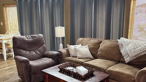 A living room with a brown leather recliner, a brown sofa, a wooden coffee table, and a ceiling fan. - Waterpark passes included Bridges Bay Resort Arnold Park/Okoboji. (Arnolds Park)