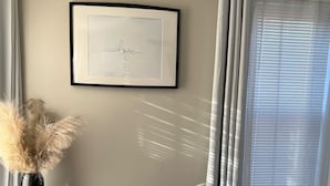 A hotel room with a bed, a framed picture on the wall, and a window with curtains.