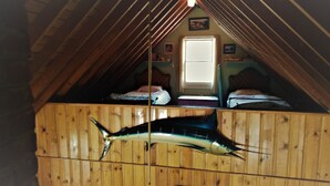 A room with wooden walls and a sloped ceiling, featuring a bed and a window.