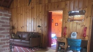A wooden interior with a leather sofa, a desk with a chair, and a large fish mounted on the wall.