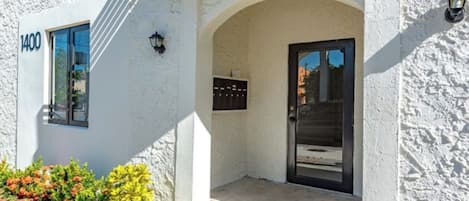 A white building with a black door and a mailbox.