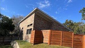 Une maison moderne en briques, avec un toit en pente et une clôture en bois.