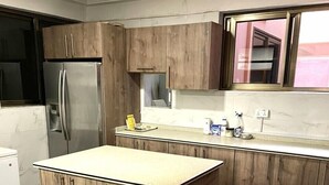 Cozinha moderna com armários de madeira, geladeira de aço inoxidável e bancada de mármore.