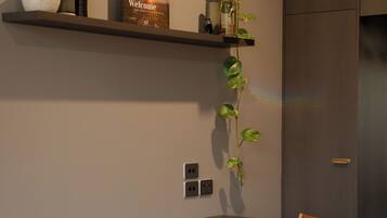 Een moderne kamer met een houten stoel, een plank met decoratieve objecten en een deur.