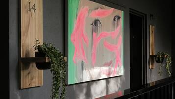 A hallway with numbered wooden panels, a large abstract painting, and potted plants.