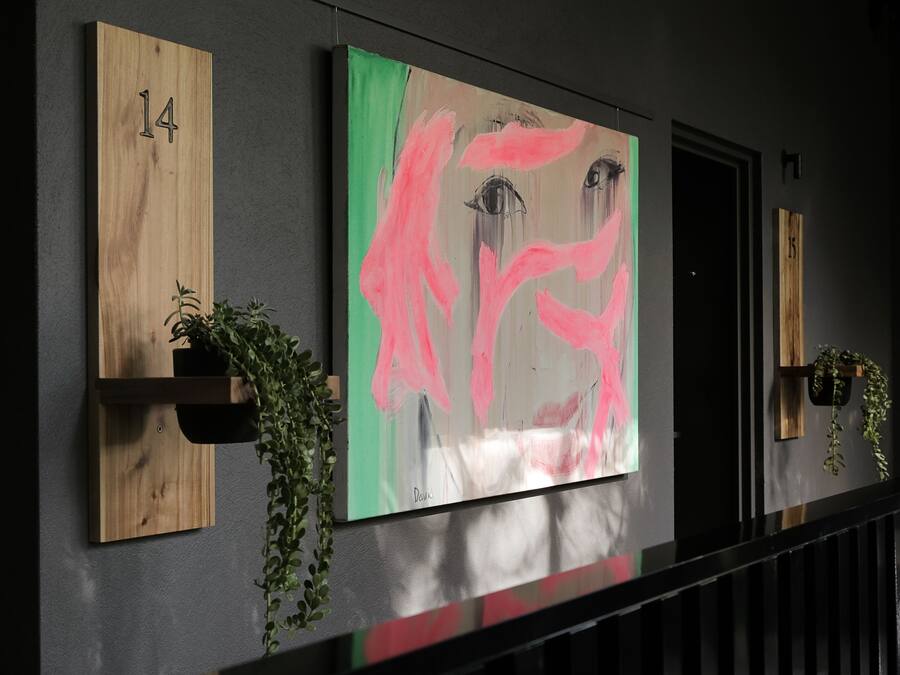 A hallway with numbered wooden panels, a large abstract painting, and potted plants.