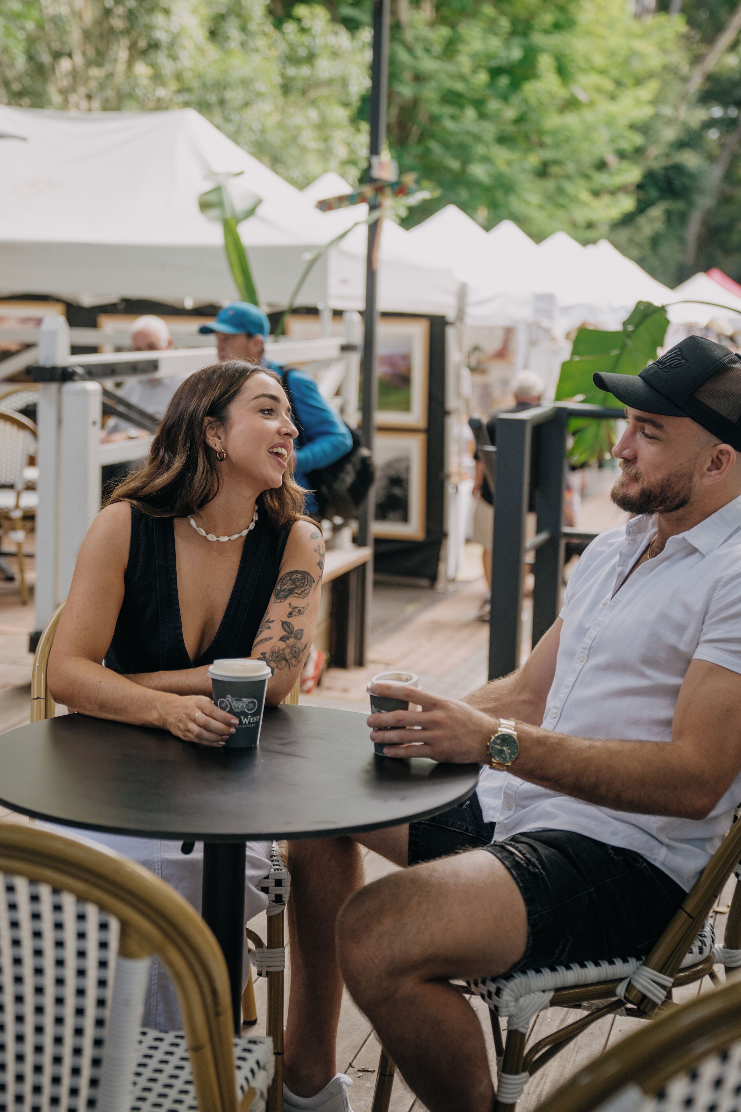 Two people seated at an outdoor table with a white umbrella in the background.