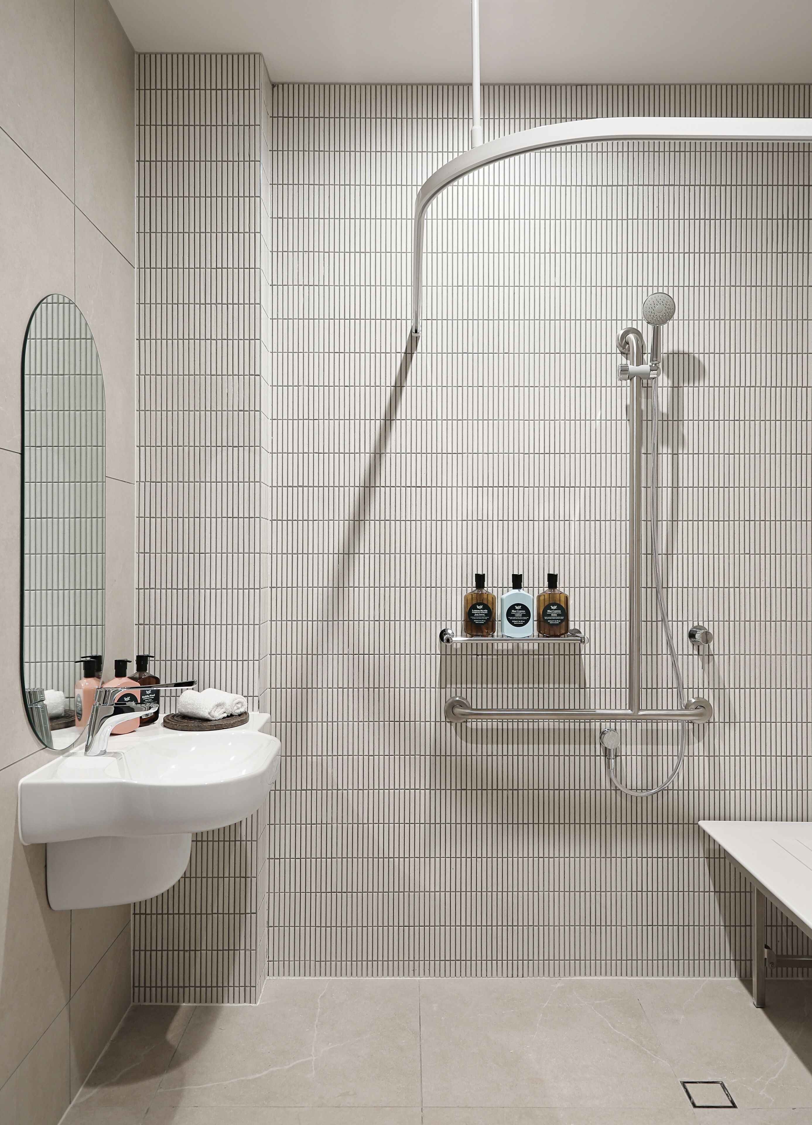 A modern bathroom with a white sink, mirror, and shower.