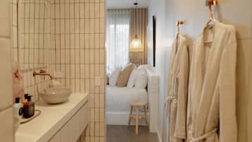 Une salle de bain moderne avec un grand miroir, un lavabo sur colonne, une baignoire et un tabouret en bois.