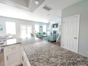 A spacious kitchen with granite countertops, white cabinetry, and a dining area with a table and chairs.