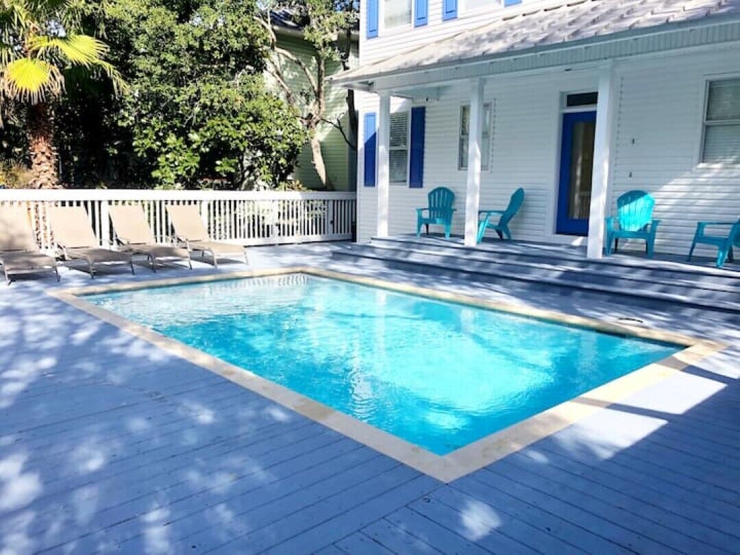 A swimming pool with lounge chairs and a deck.