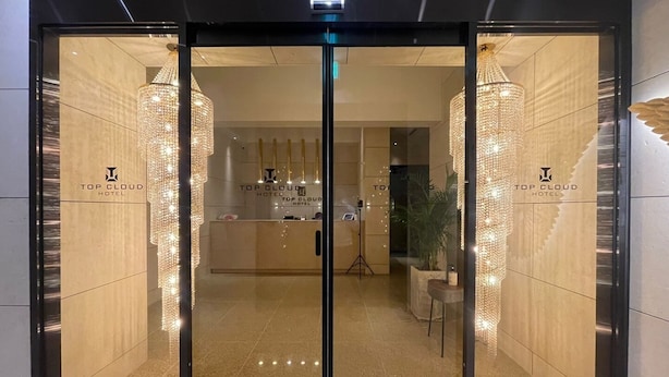 Entrada de hotel con diseño moderno, que incluye una recepción y una lámpara de araña.