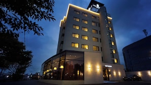 Un hotel moderno con fachada de vidrio, varios pisos y un letrero en la azotea.