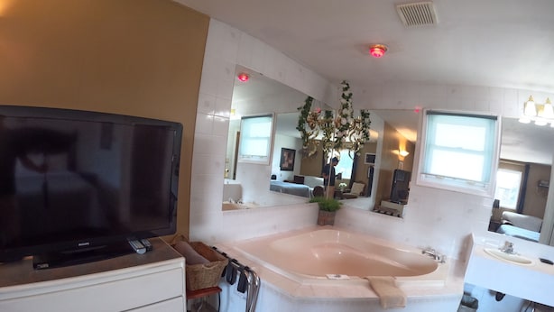 Un baño moderno con una bañera grande, un tocador con lavamanos y un televisor sobre un mueble.