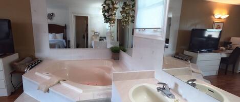 A modern bathroom with a large bathtub, a vanity with a sink, and a large mirror.
