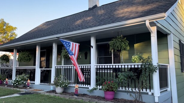 A house with a porch, American flag, and potted plants.
