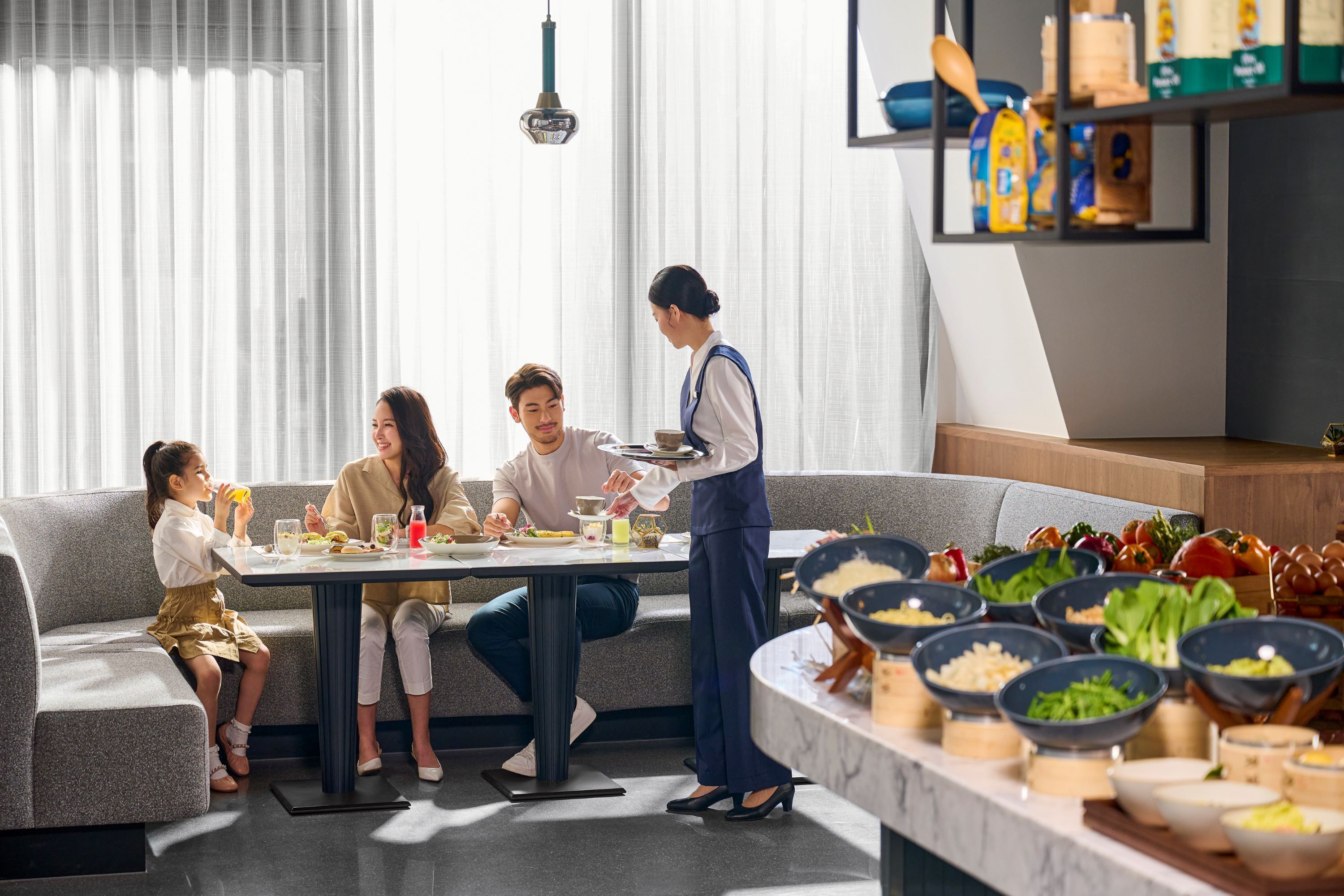 Un área de comedor moderna con un bufé, un sofá y una persona sirviendo comida.
