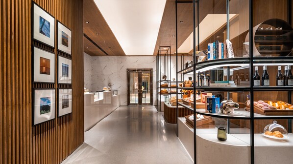 A modern hotel lobby with a marble floor, wooden paneling, and a glass display case with pastries and books. - InterContinental Kaohsiung by IHG (Kaohsiung)