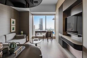 A modern living room with a sofa, coffee table, and TV. It features a large window with a city view. - InterContinental Kaohsiung by IHG (Kaohsiung)