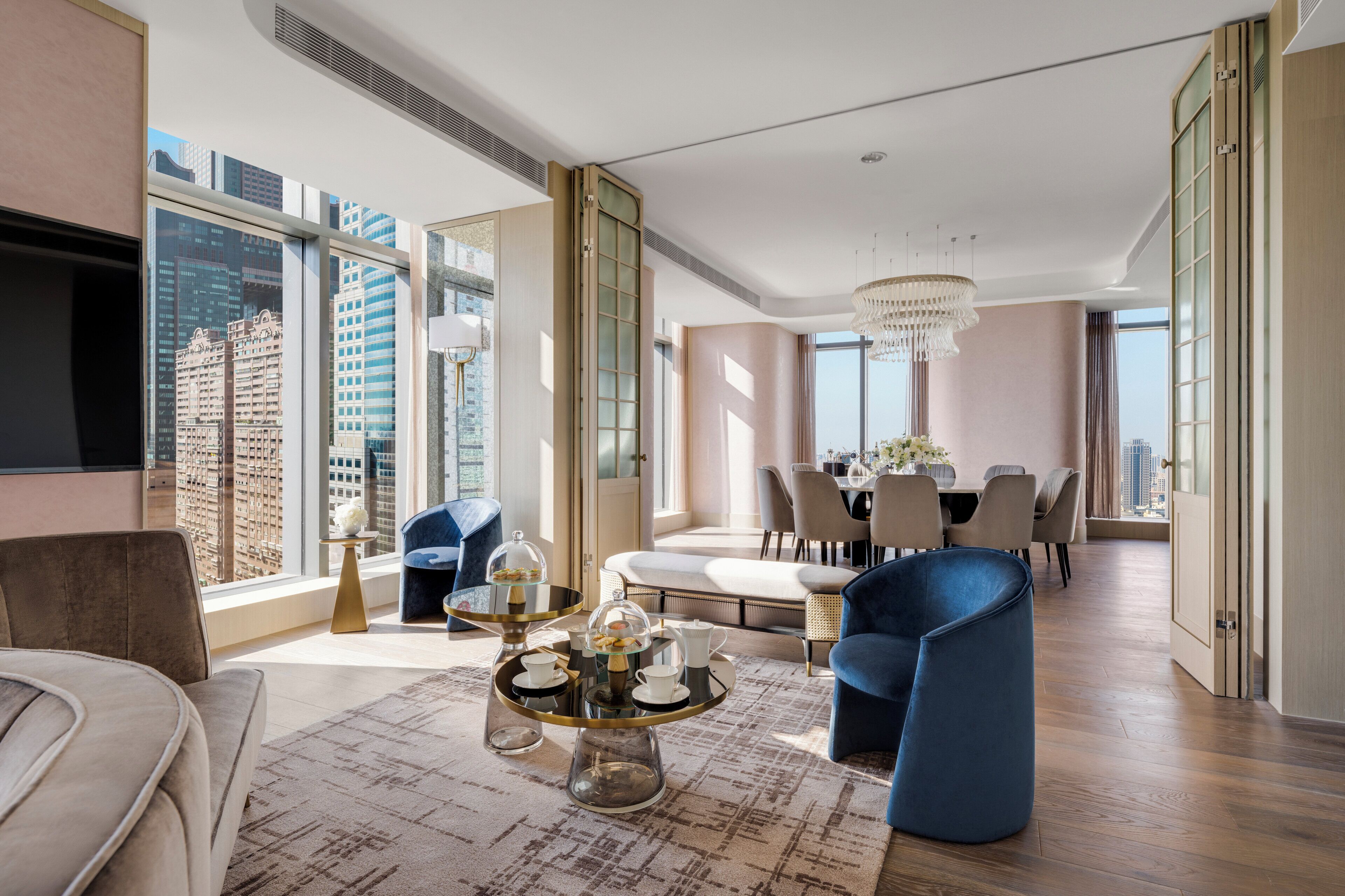 A modern living room with a large window, a dining area, and a seating arrangement.