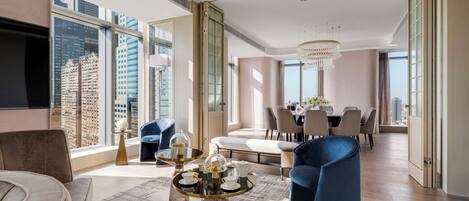 A modern living room with a large window, a dining area, and a seating arrangement.