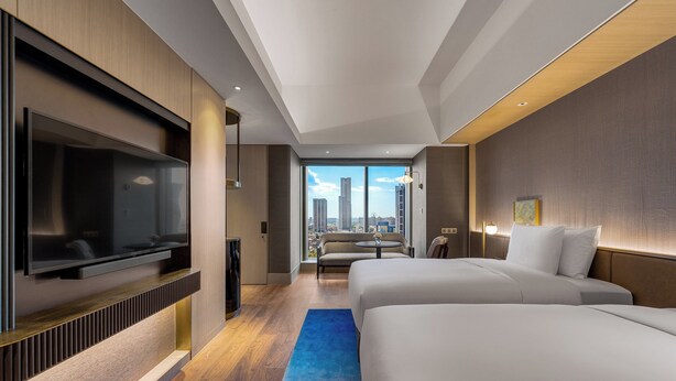 A modern hotel room with a large TV, two beds, a sofa, and a city view. - InterContinental Kaohsiung by IHG (Kaohsiung)