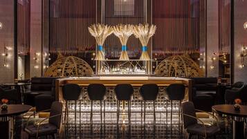 A bar area with a central counter, multiple seating arrangements, and decorative elements.