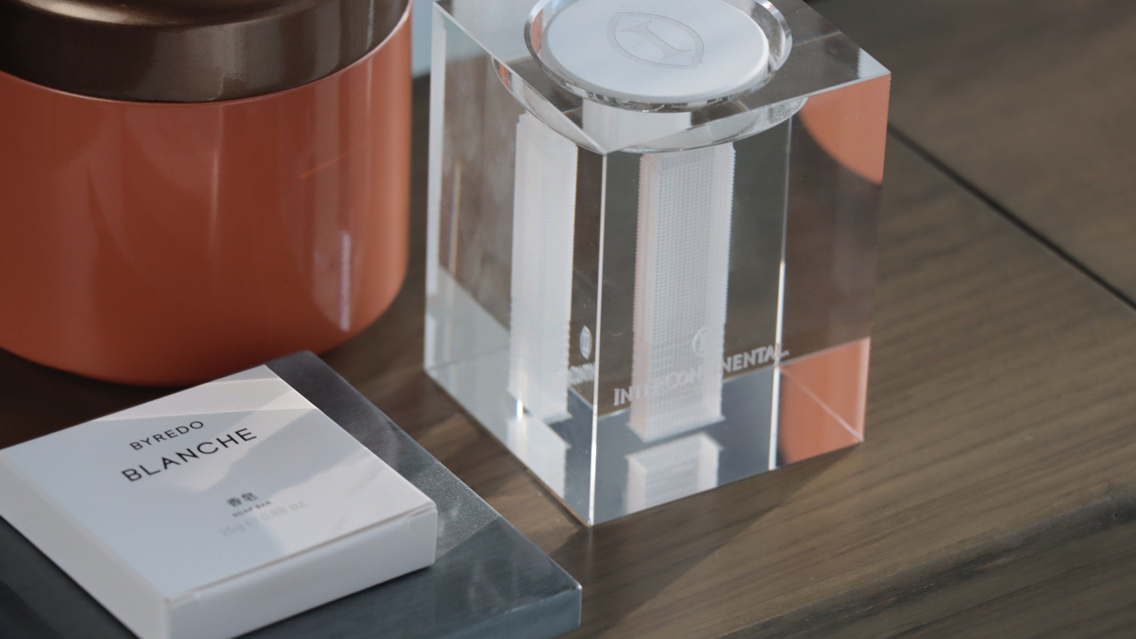 A clear glass bottle with a label, a white box with text, and a metallic container with a lid.